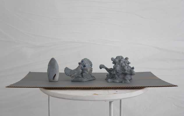 3 grey painted blobby sculptures on a table