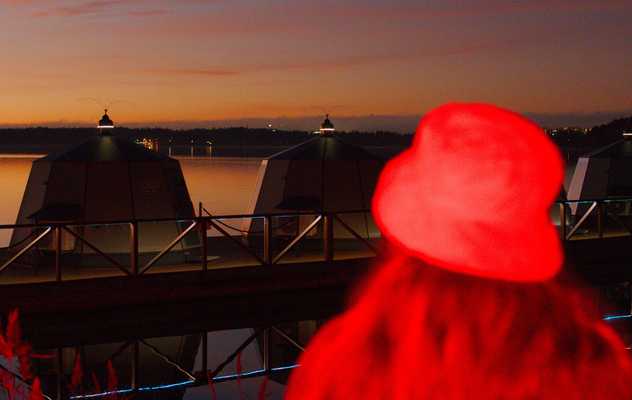 A mysterious figure in a bucket hat agains a sunset filled with red light