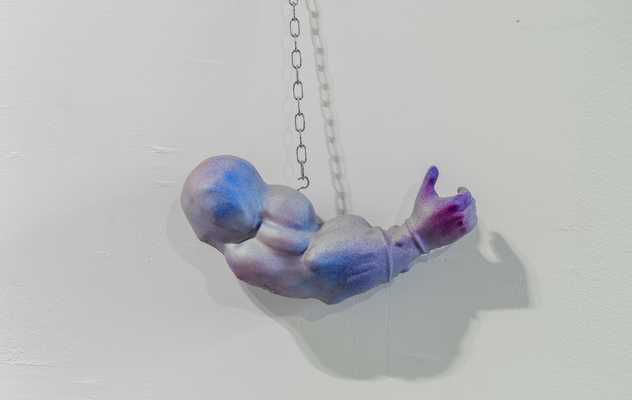 A muscular arm 3d printed sculpture hanging by a chain on the wall